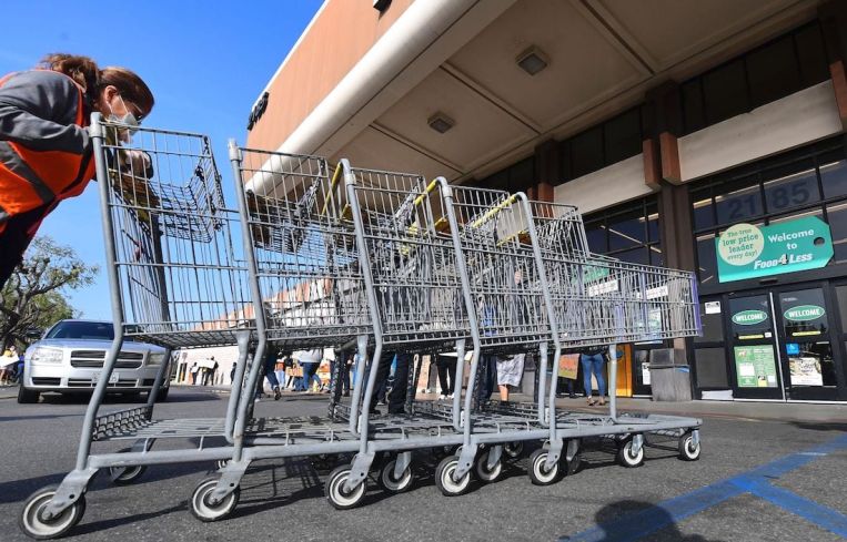 A Food 4 Less employee pushes carts past supermarket workers gathered to protest in front of the supermarket in Long Beach after a decision by Kroger to close two supermarkets rather than pay workers an additional $4 in "hazard pay."