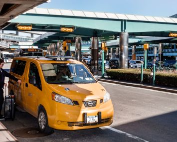 A taxi picking up a passenger outside LaGuardia Airport.
